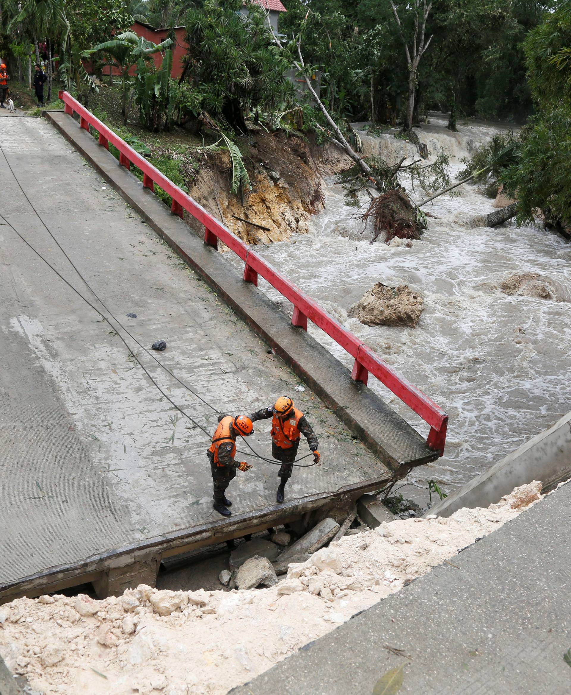 Members of Guatemalan emergency commission (CONRED) stand at a bridge that collapsed after heavy rains brought by Hurricane Earl at Menchor de Mencos