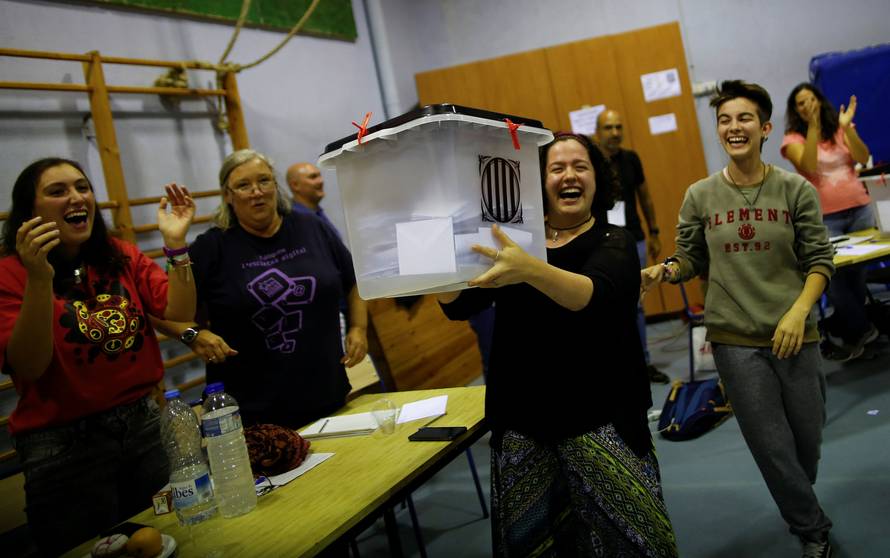 Poll workers lift a ballot box in celebration after polls closed at a polling station for the banned independence referendum in Barcelona