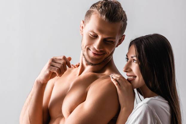 Pretty woman hugging shirtless boyfriend in bedroom