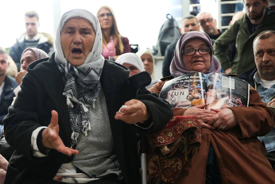 A woman reacts as she watches a television broadcast of the court proceedings of former Bosnian Serb general Ratko Mladic in the Memorial centre Potocari near Srebrenica
