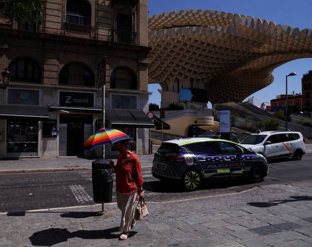 A woman carries an umbrella nearby Las Setas during a heatwave in Seville