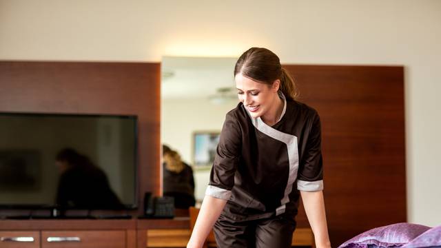 Hotel maid arranging the bed sheets