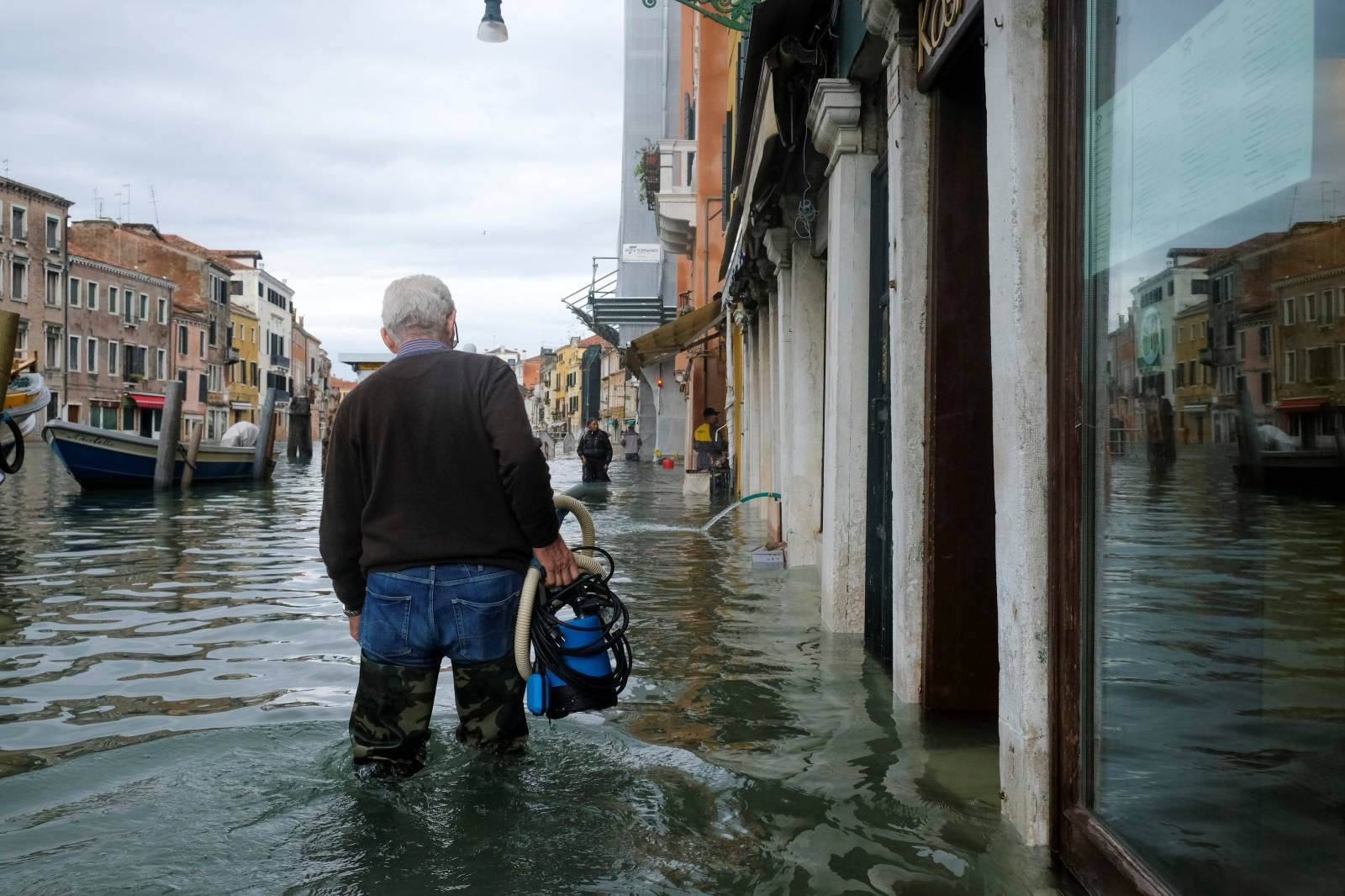 A man walks in the flooded street during a period of seasonal high water in Venice