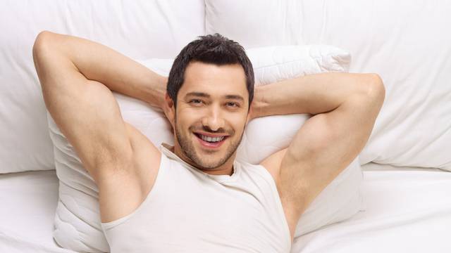 Young man lying in a bed and smiling