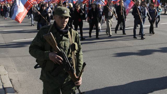 People carry flags of self-proclaimed Donetsk People's Republic as they attend rally marking third anniversary of referendum on secession in rebel-controlled city of Donetsk