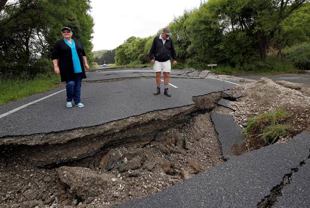 Local residents Chris and Viv Young look at damage caused by an earthquake along State Highway One near the town of Ward, south of Blenheim on New Zealand