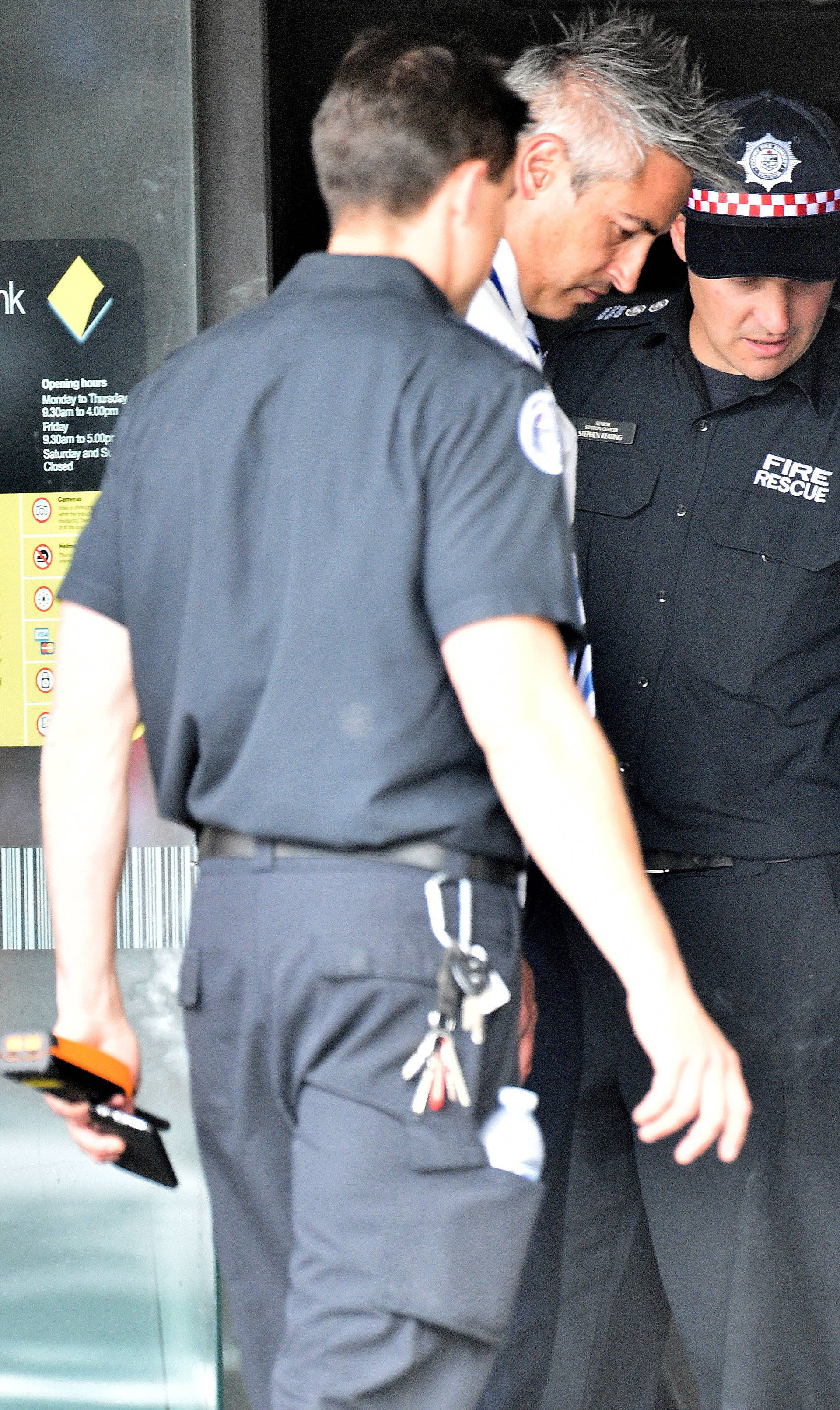 Emergency service workers are seen at a branch of the Commonwealth Bank after a fire injured customers in Melbourne