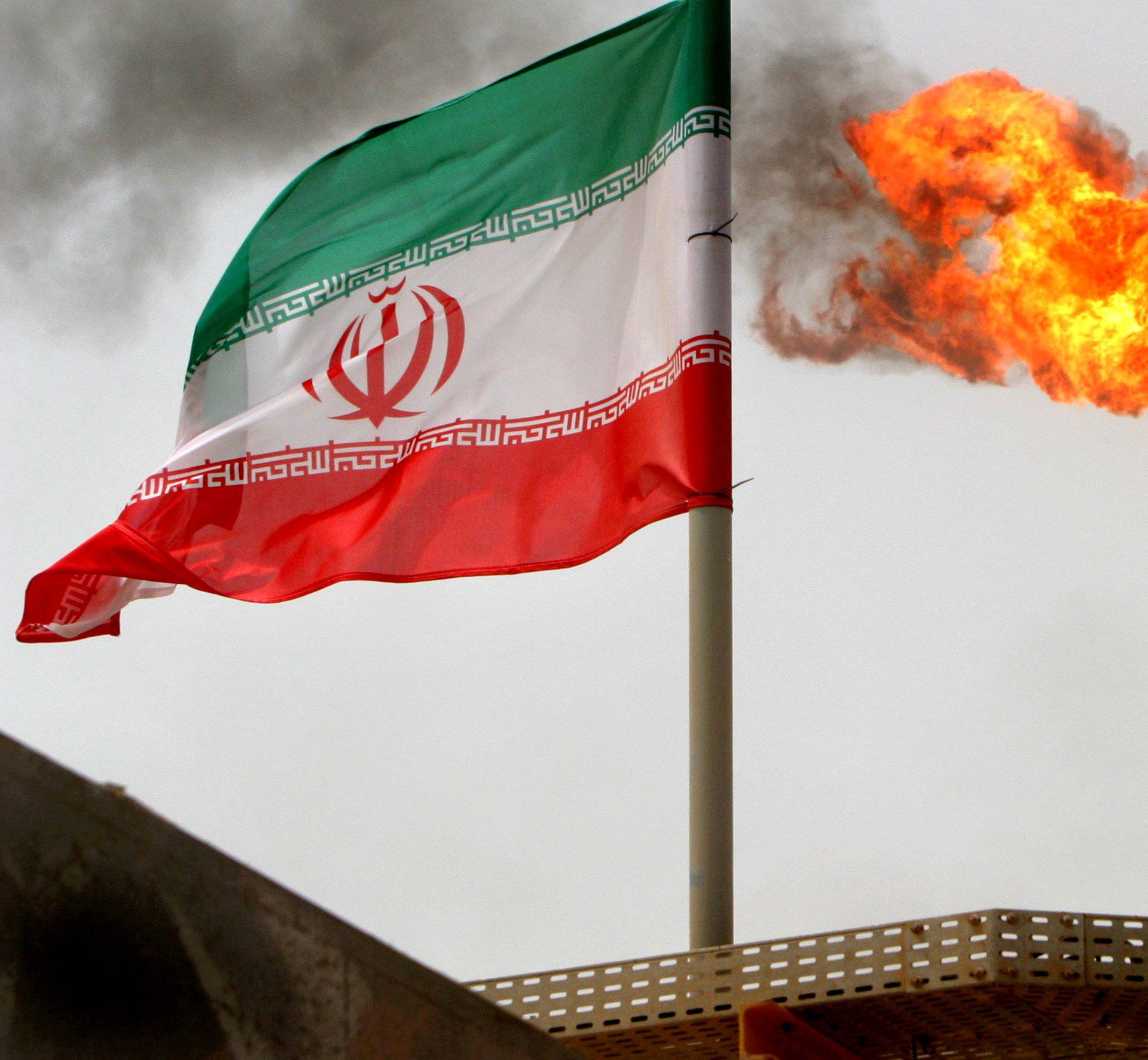 FILE PHOTO: A gas flare on an oil production platform in the Soroush oil fields is seen alongside an Iranian flag in the Persian Gulf