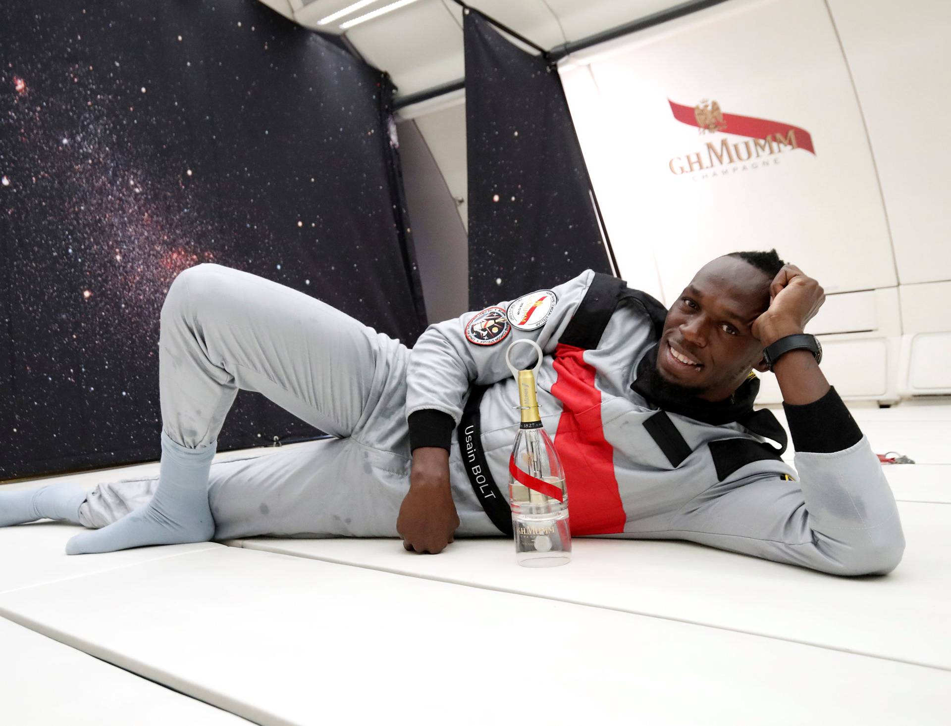Retired sprinter Usain Bolt poses with a bottle of "Mumm Grand Cordon Stellar" champagne as he enjoys zero gravity conditions during a flight in a specially modified Airbus Zero-G plane above Reims