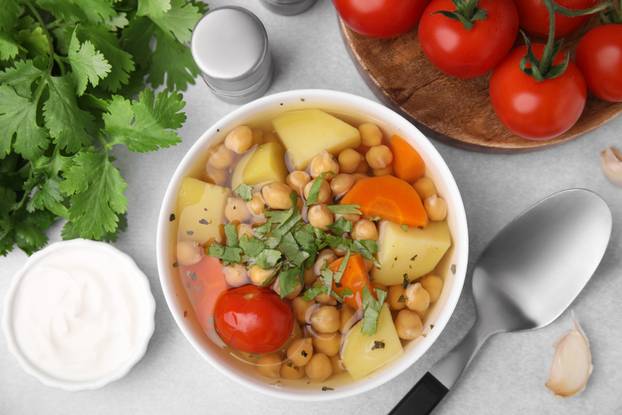 Flat lay composition of tasty chickpea soup in bowl, vegetables,