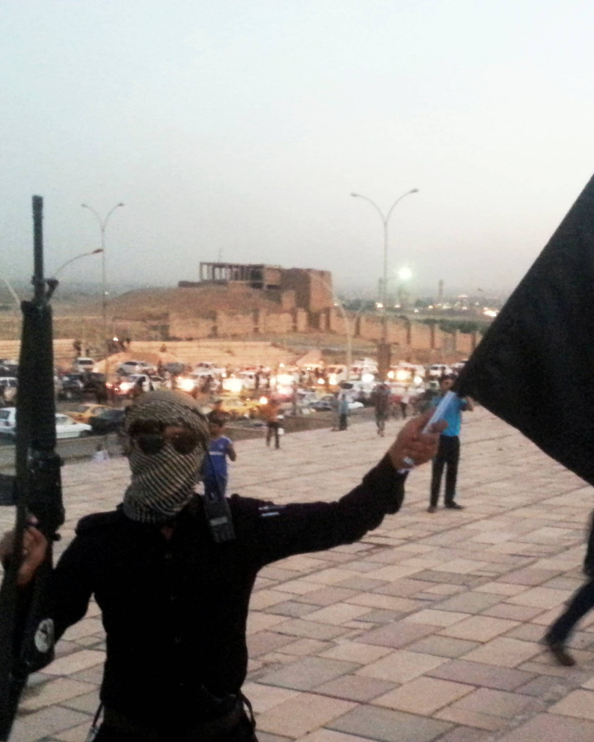 FILE PHOTO: A fighter of the ISIL holds a flag and a weapon on a street in Mosul