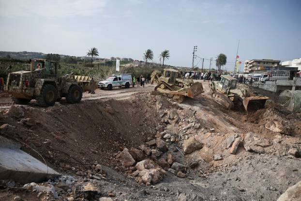 Displaced people cross the bridge linking southern Lebanon to the rest of the country, which was hit earlier in an Israeli strike, in Qasmiyeh