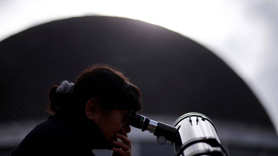 A woman uses a telescope to observe the planet Mercury transit in front of the sun outside Buenos Aires' planetarium