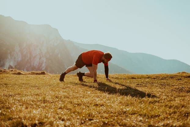 A determined athlete preparing for the start of training on the top of the mountain at sunrise.