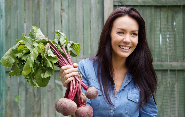 Smiling vegetarian woman holding bunch of beetroots