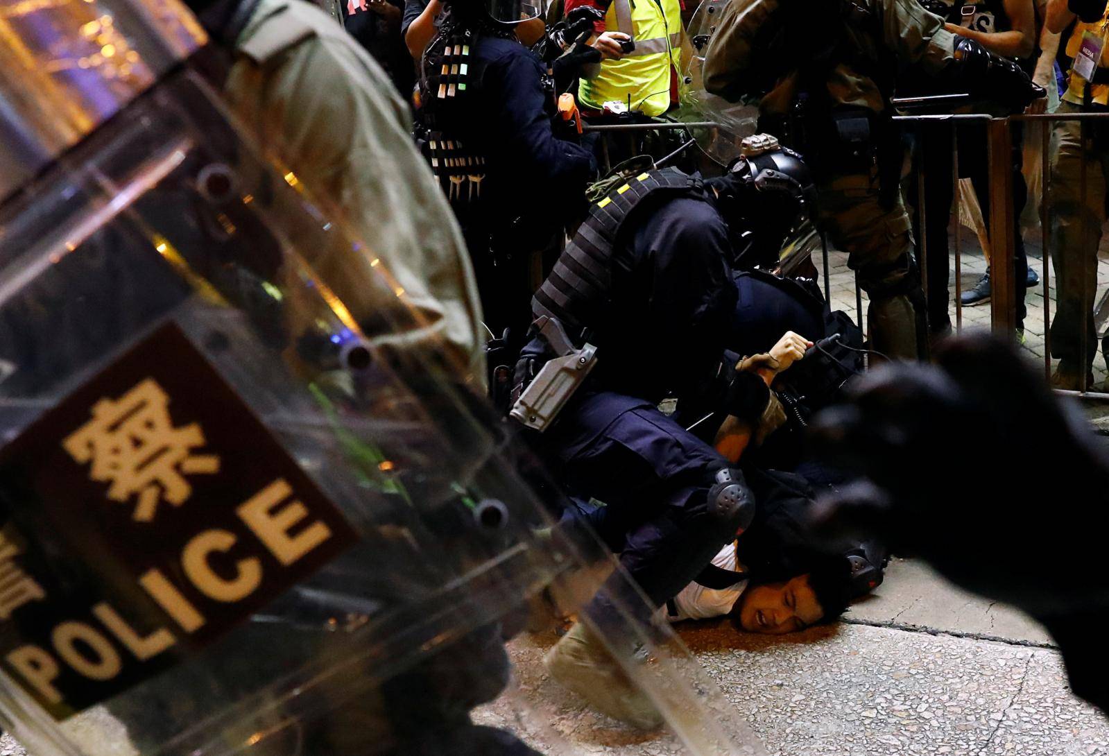A police officer detains a person near Mong Kok police station in Hong Kong