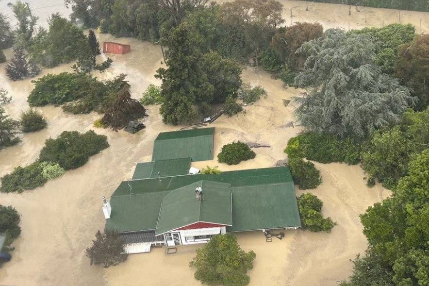 An NH90 helicopter and crew recover people from the rooftops of their homes in Esk Valley, Napier