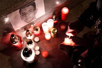 A journalist lights a candle in memory of murdered investigative journalist Jan Kuciak, in Trencin