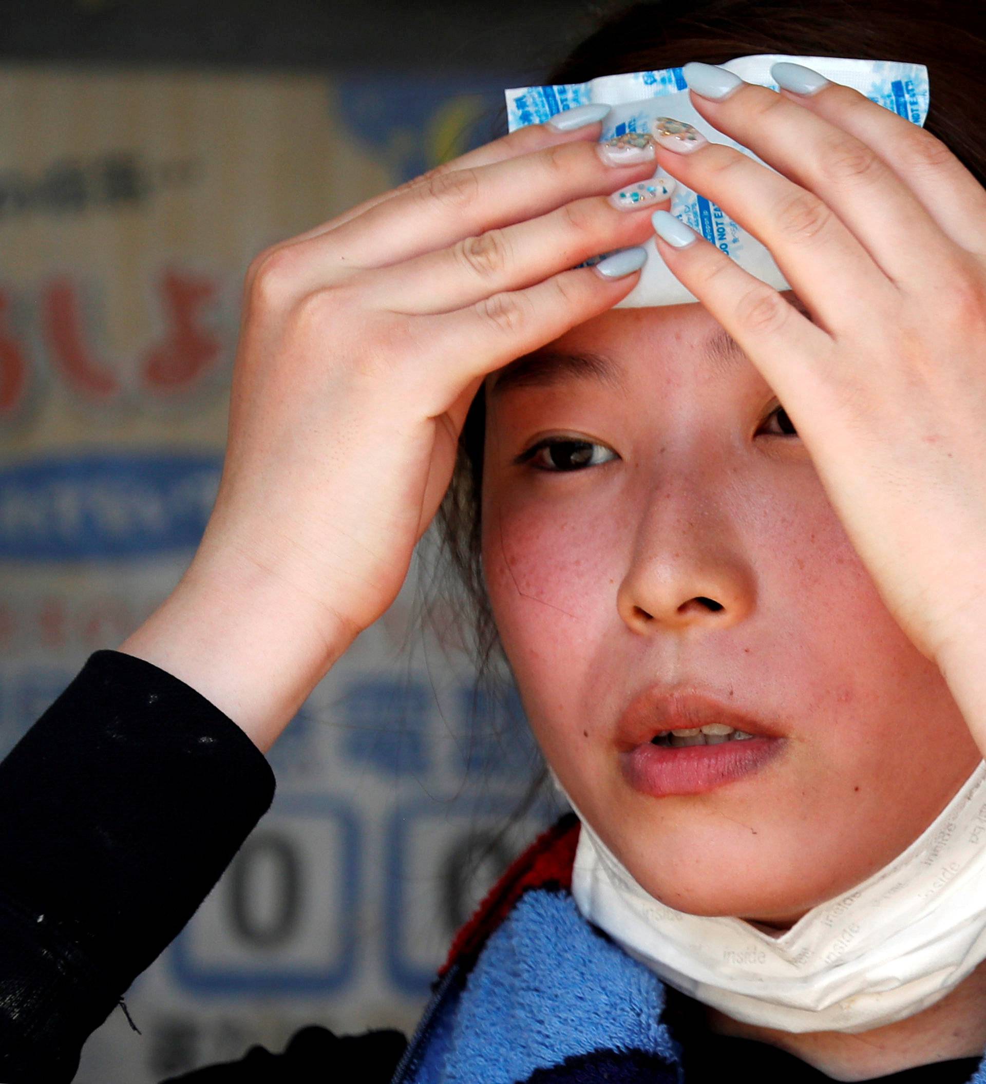 FILE PHOTO: A volunteer, for recovery work, uses a pack of refrigerant to a cool down as she takes a break in a heat wave at a flood affected area in Kurashiki