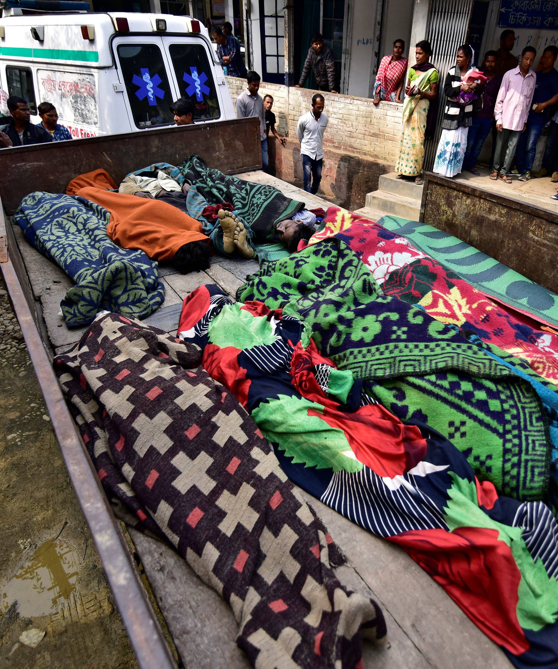 People look at the bodies of tea plantation workers, who died after consuming bootleg liquor, outside a government-run hospital in Golaghat
