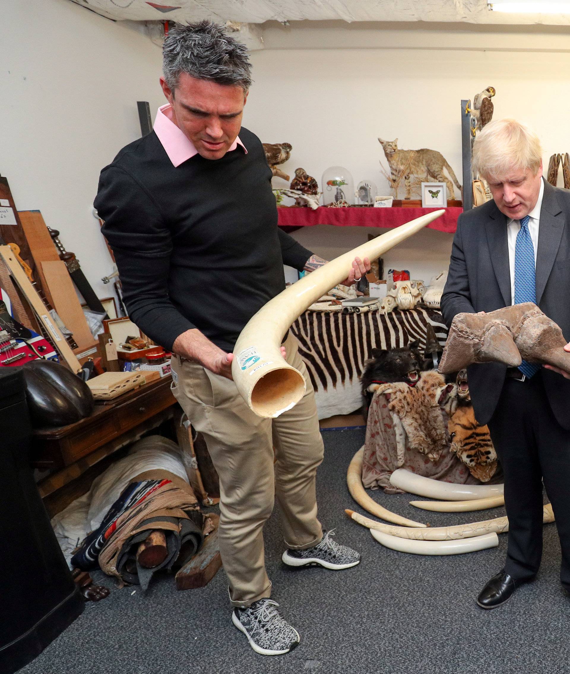 Former England cricketer Kevin Pietersen and Britain's Foreign Secretary Boris Johnson visit the ÃDead ShedÃ at Heathrow Airport, to observe items relating to the illegal wildlife trade, in west London