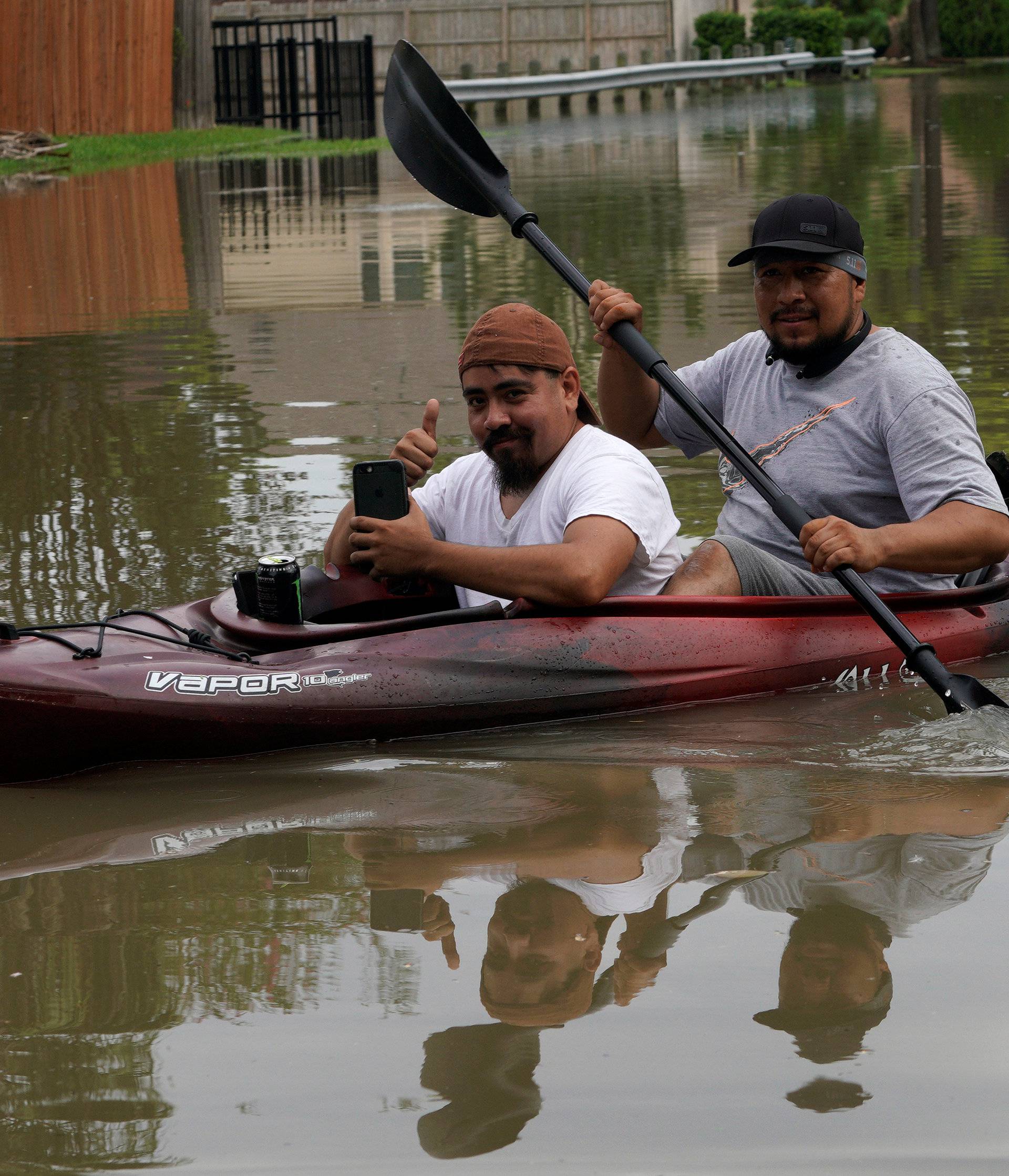 Two men take their possessions out of Tropical Storm Harvey floodwaters by kayak in north western Houston
