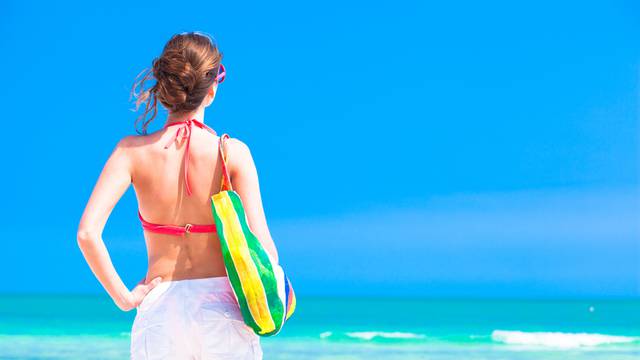 Woman in bikini and sunglasses with beach bag