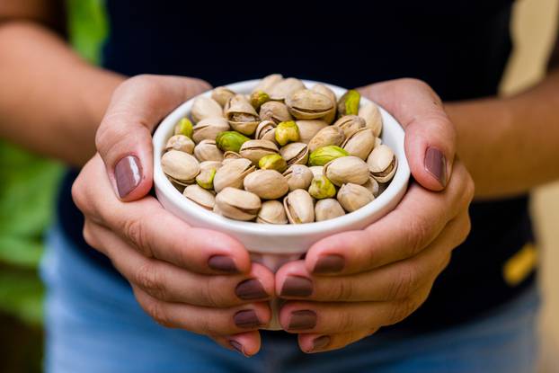Hand,Of,Brunette,Model,Holding,White,Pot,With,Pistachio.