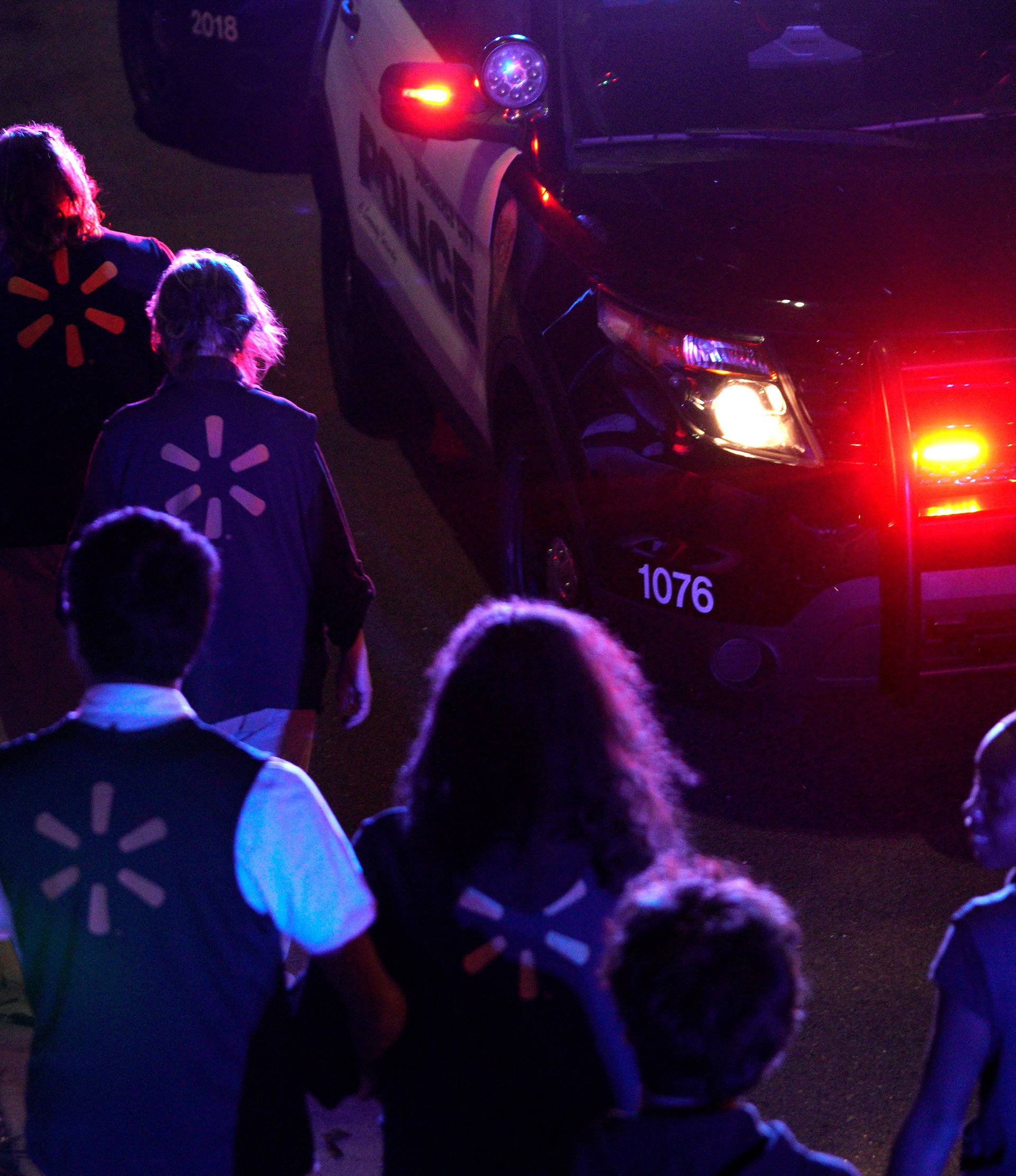 Walmart employees walk to a police staging area at the scene of a shooting at a Walmart in Thornton