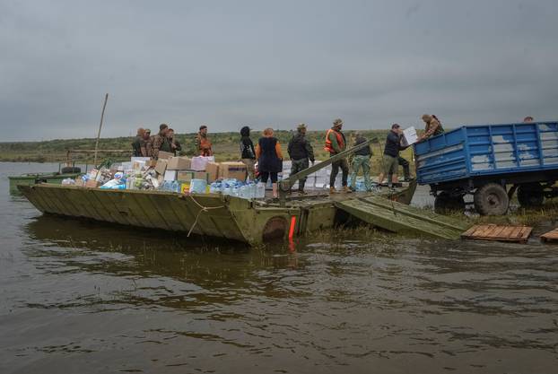 Ukrainian servicemen unload humanitarian aid for local residents after the Nova Kakhovka dam breached, in the flooded village of Afanasiivka
