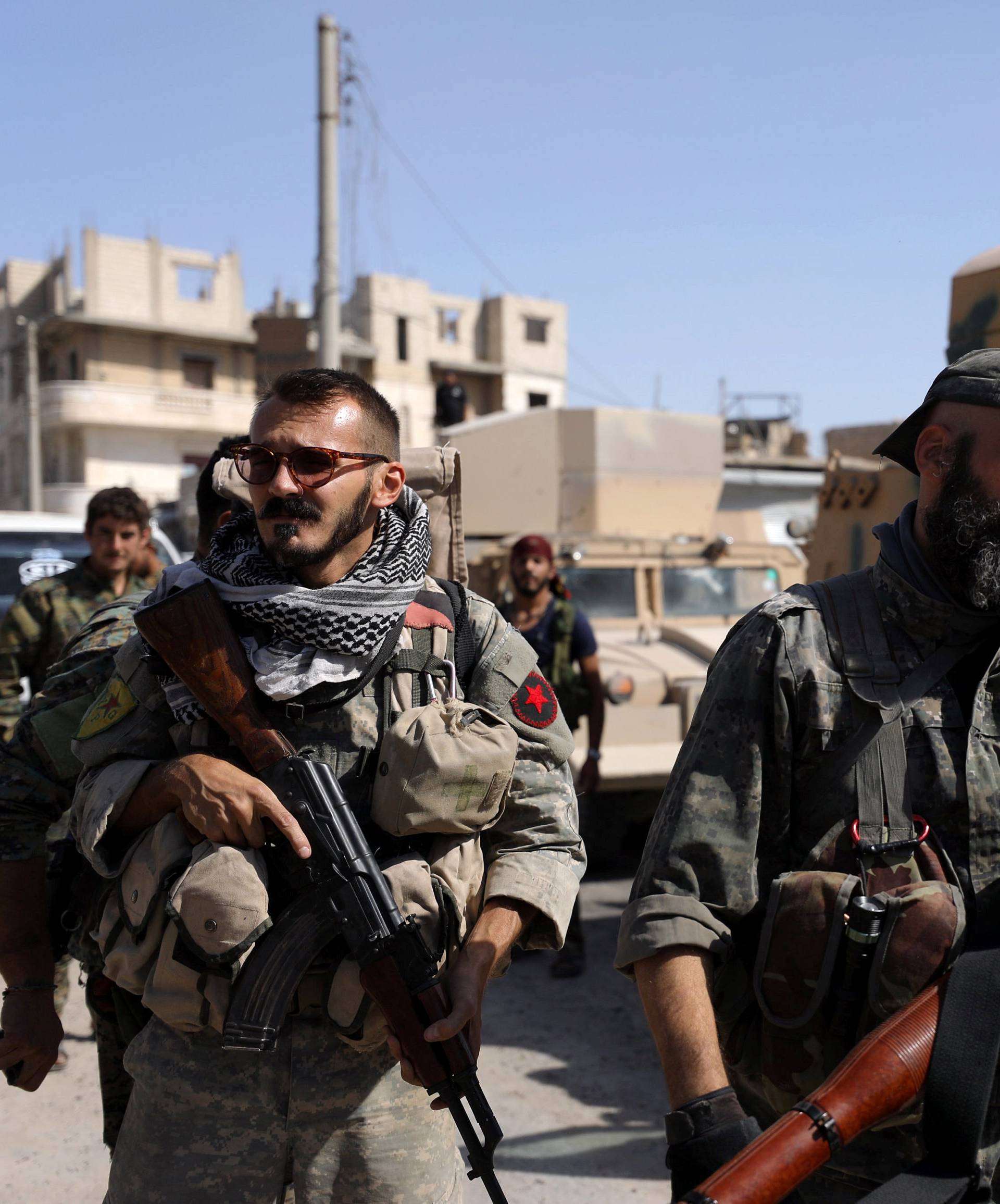 Fighters of Syrian Democratic Forces carry weapons at the frontline in Raqqa