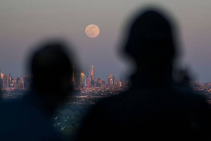 People watch the full moon, known as the "Super Pink Moon", as it rises over the skyline of New York and Empire State Building, as seen from West Orange, in New Jersey