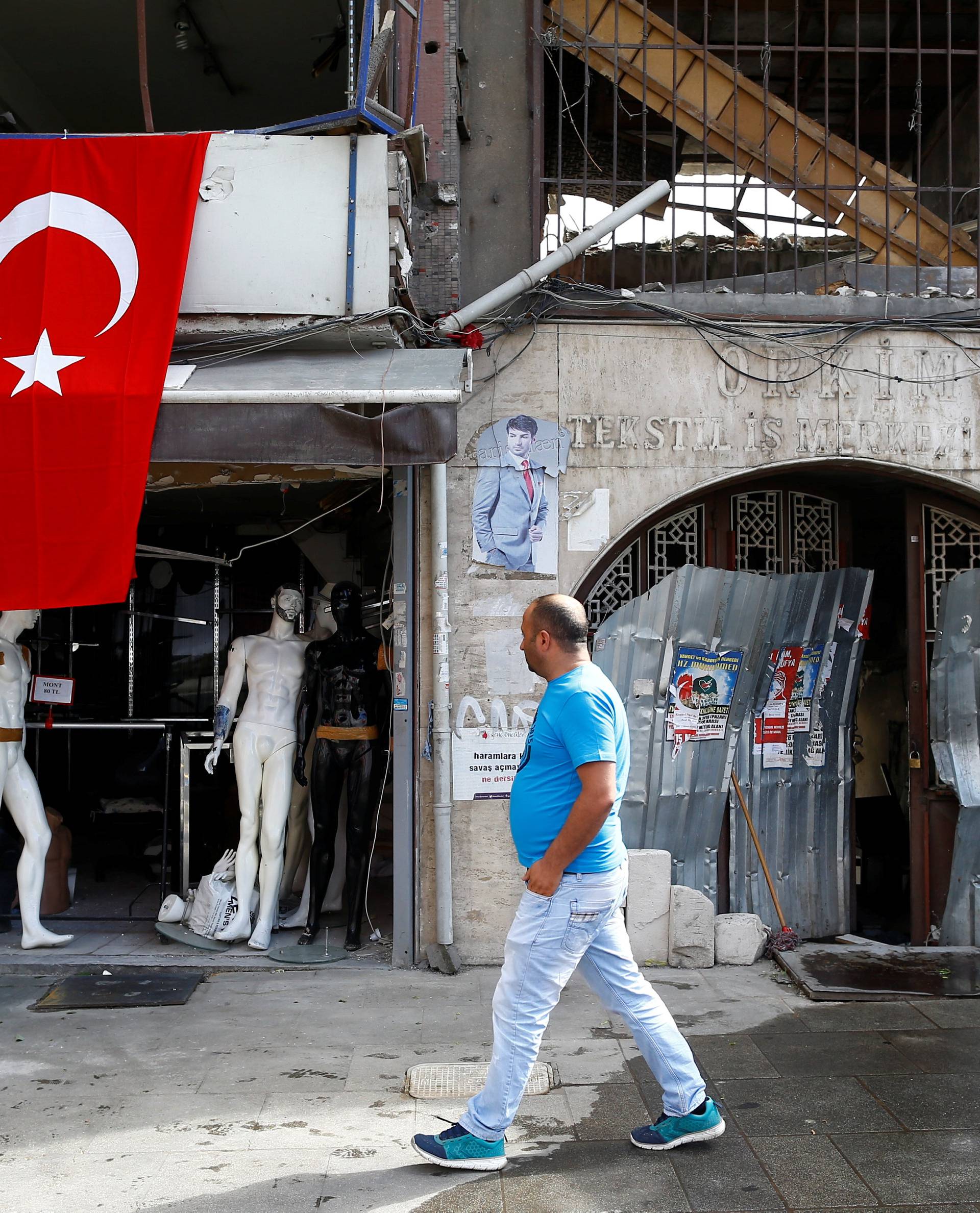 A man walks past by a damaged shop near the scene of Tuesday's car bomb attack on a police bus, in Istanbul