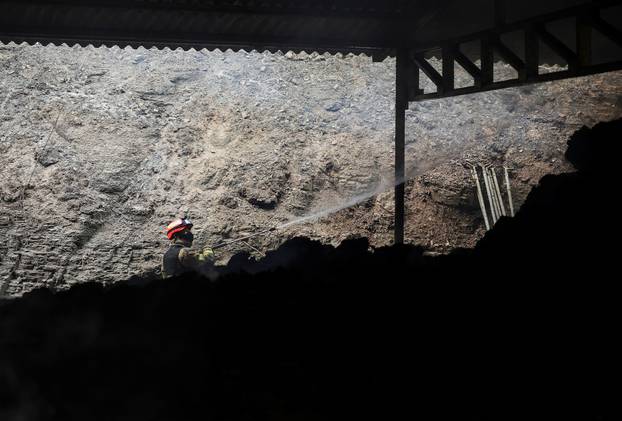 A firefighter works at a partially burnt down cattle farm after a wildfire devastated the area, in Uiseong