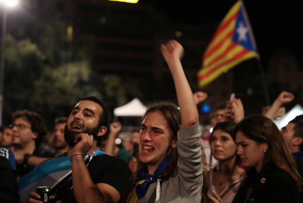 People react as they listen to Catalan president Carles Puigdemont during a gathering at Plaza Catalunya after voting ended for the banned independence referendum, in Barcelona