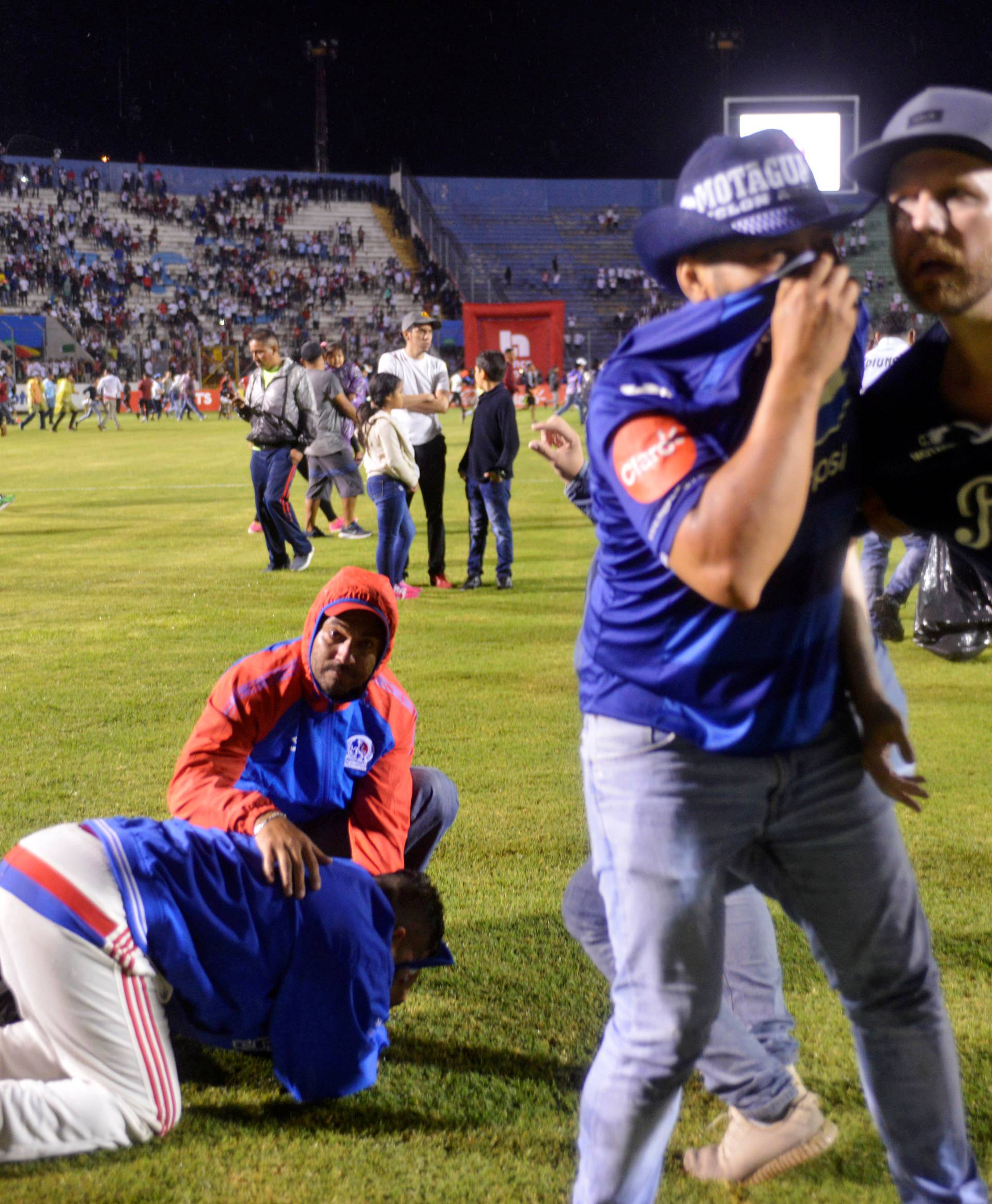 Spectators react from tear gas after three people died in riots before a soccer match when the fans attacked a bus carrying one of the teams, at the National Stadium in Tegucigalpa