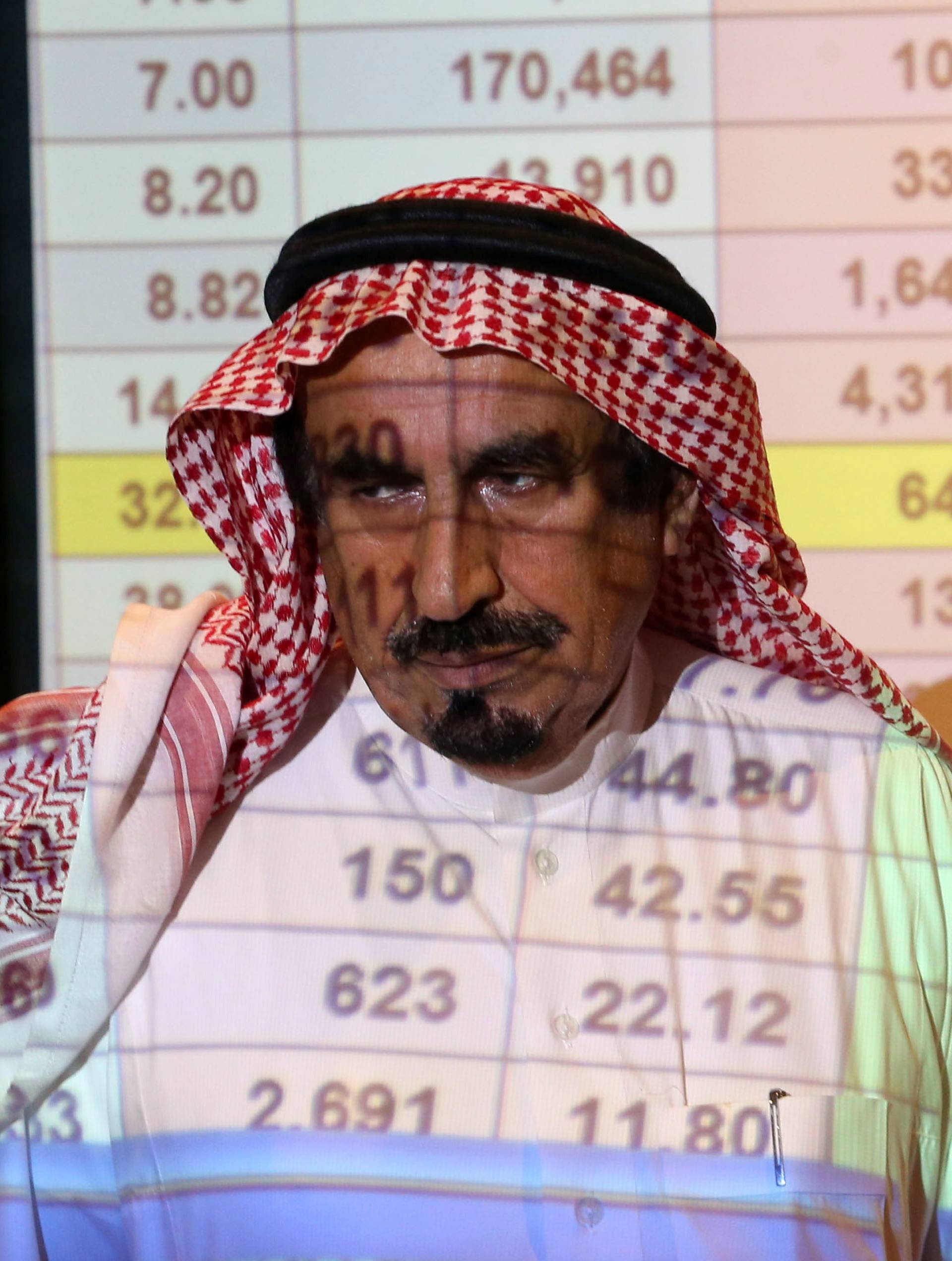 Saudi man stands in front of a screen showing stock prices at ANB Bank in Riyadh