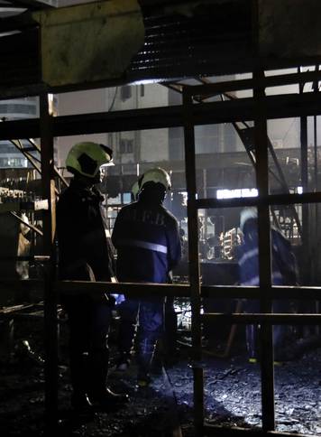 Firemen inspect the debris after a fire at a restaurant in Mumbai