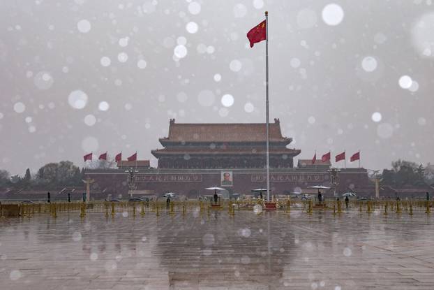 Chinese national flag flutters near Tiananmen Gate amid snowfall before the opening sessions of the annual CPPCC
