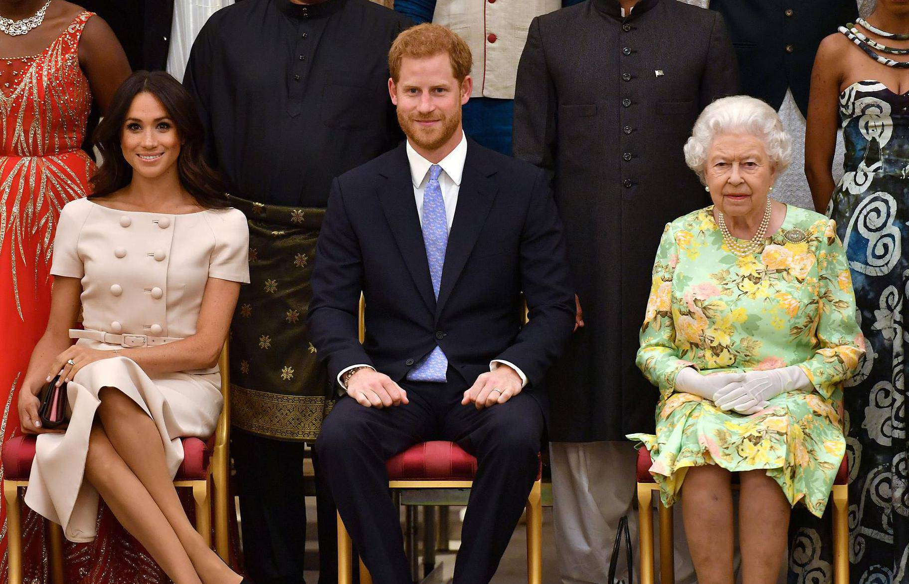 FILE PHOTO: Britain's Queen Elizabeth, Prince Harry and Meghan, the Duchess of Sussex pose for a picture with some of Queen's Young Leaders at a Buckingham Palace reception following the final Queen's Young Leaders Awards Ceremony, in London