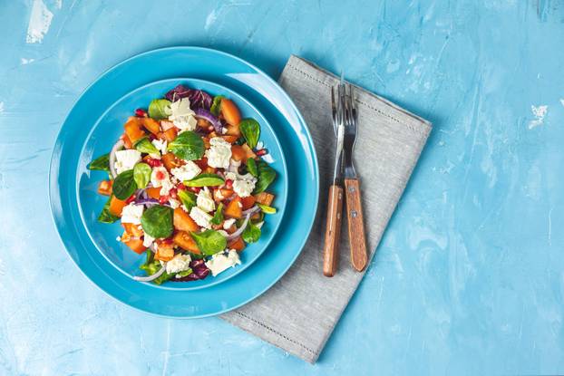 Blue plate of fresh superfoods healthy salad with red onion, tom