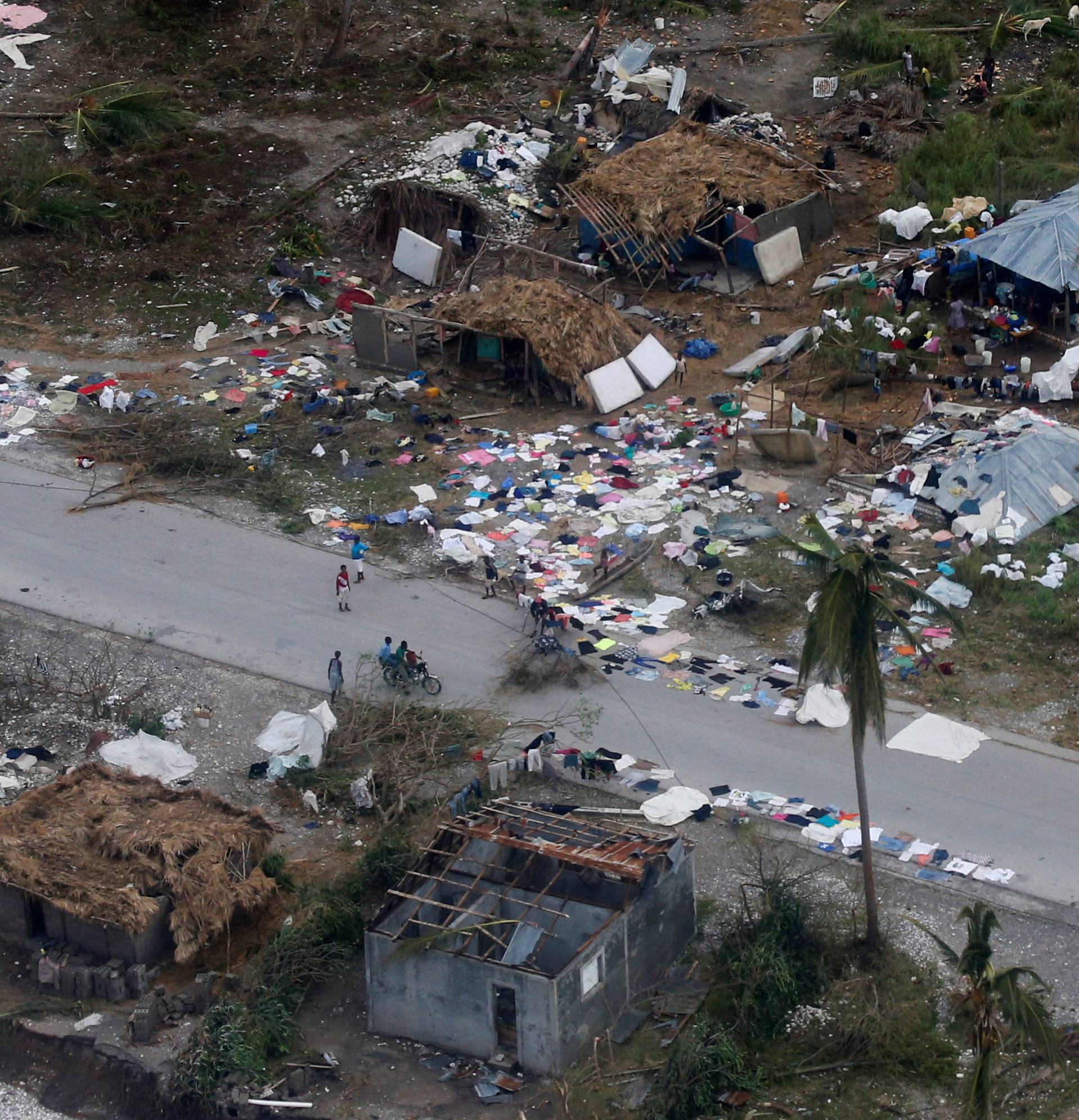 People walk down the street next to destroyed houses after Hurricane Matthew passes Jeremie, Haiti