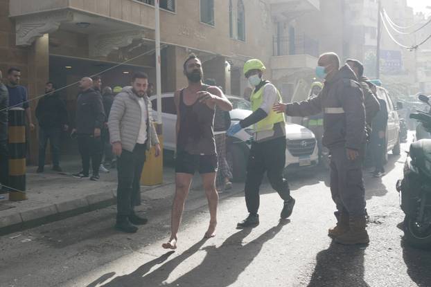 A man runs along a street among members of the Lebanese Civil Defence and civilians following an Israeli air strike in Beirut