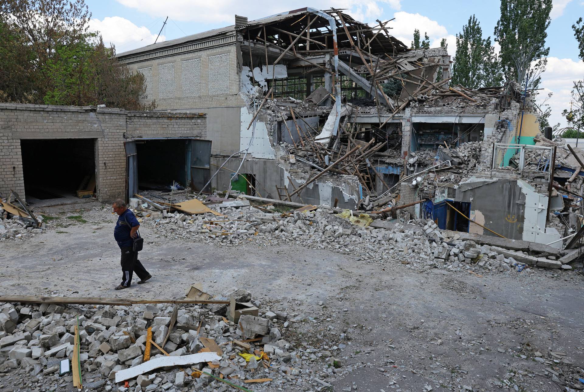 A local resident walks past a destroyed building in Lysychansk