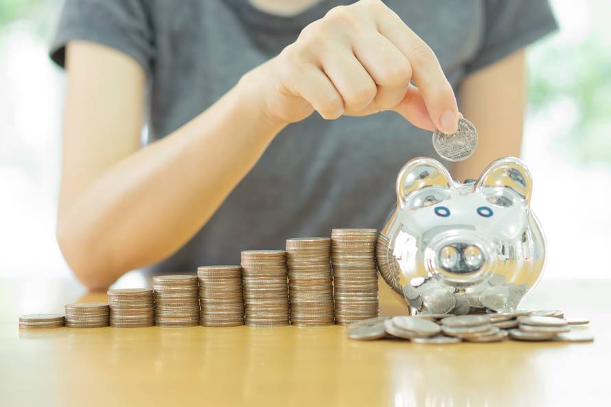 saving money-young woman putting a coin into a money-box-close u