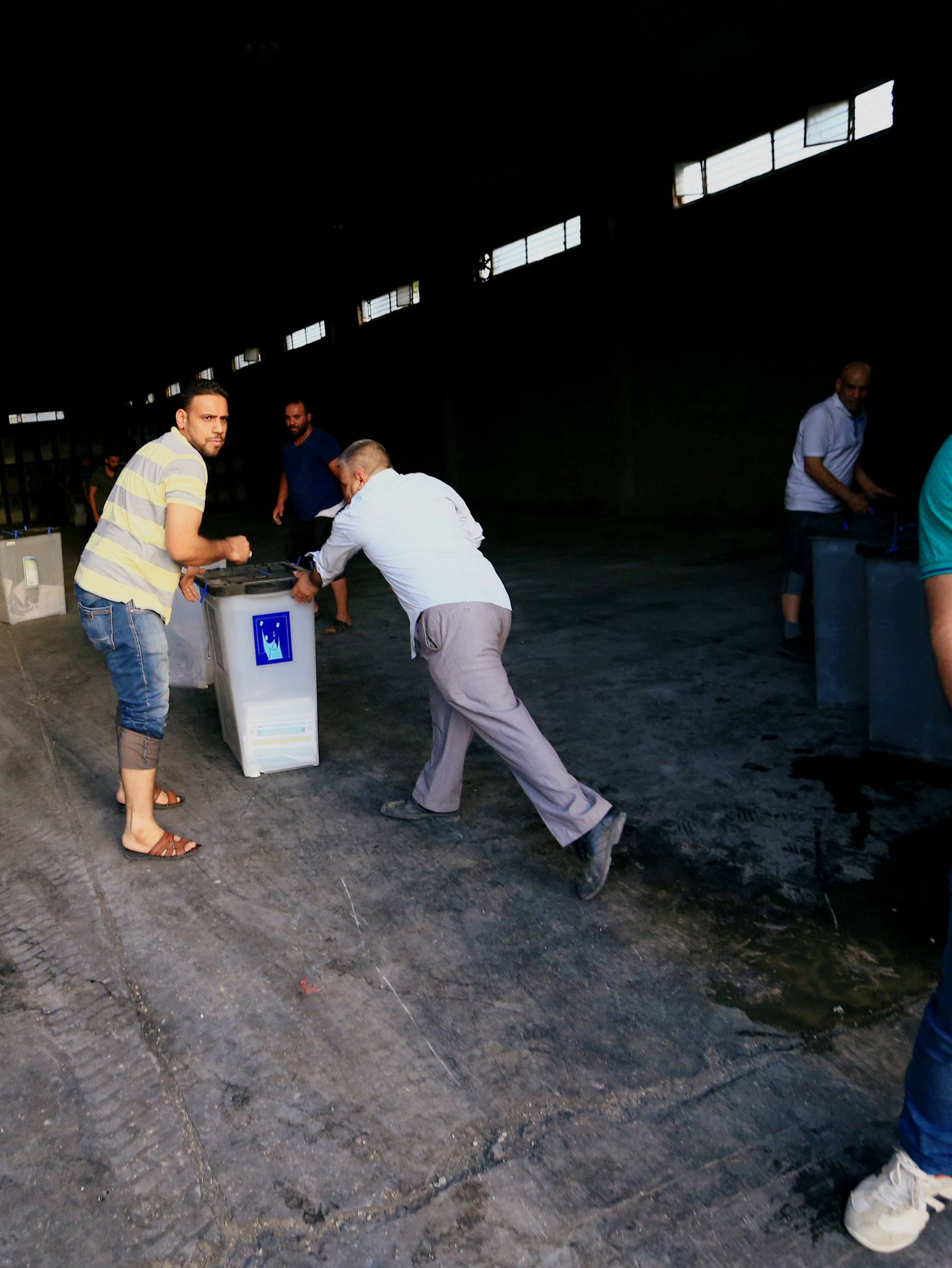 Iraqi men carry ballot boxes after a fire at a storage site in Baghdad, housing the boxes from Iraq's May parliamentary election