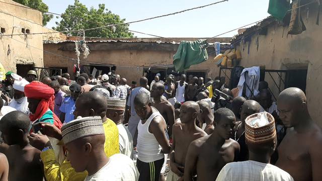 Police officers, journalists and a traditional chief stand next to people who were rescued by police in Sabon Garin, in Daura local government area of Katsina state
