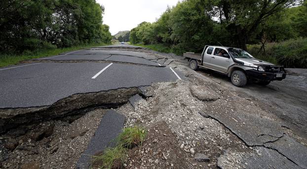 A four-wheel-drive vehicle negotiates the damaged State Highway One near the town of Ward, south of Blenheim, following an earthquake on New Zealand