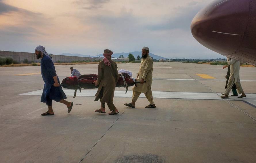 People carry an earthquake victim on a stretcher to an ambulance at an airport in Jalalabad