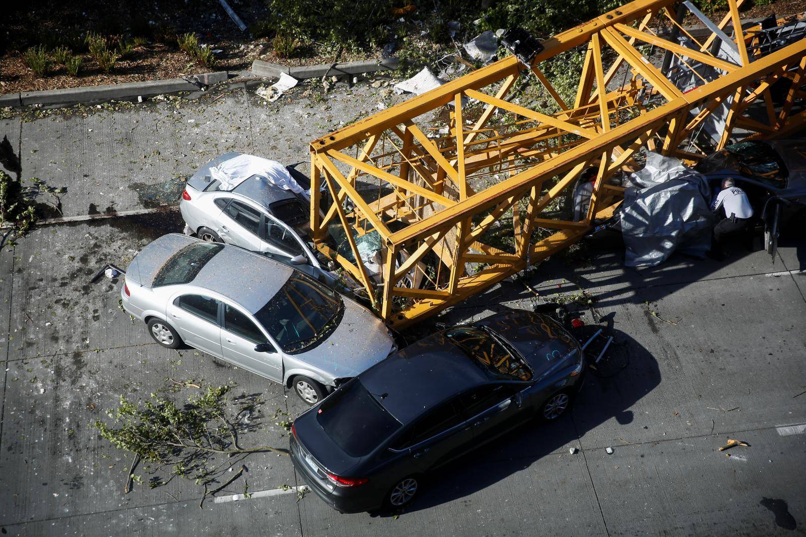 A member of the Seattle police department inspects one of the cars crushed by part of a construction crane on Mercer Street, which killed four people and injured several others in Seattle